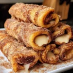 Cinnamon French Toast Roll Ups served on a plate with syrup and berries.